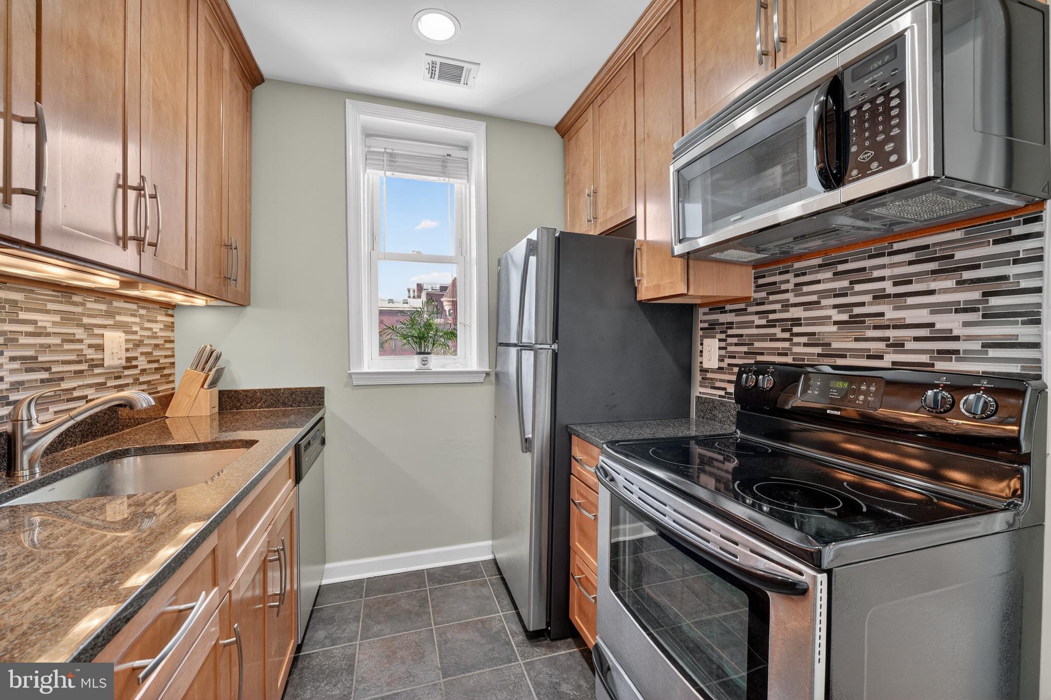 2001 16th Street Northwest, Unit 307 Washington, DC 20009 - Photo 10 of 27 a kitchen with granite countertop a stove and a refrigerator