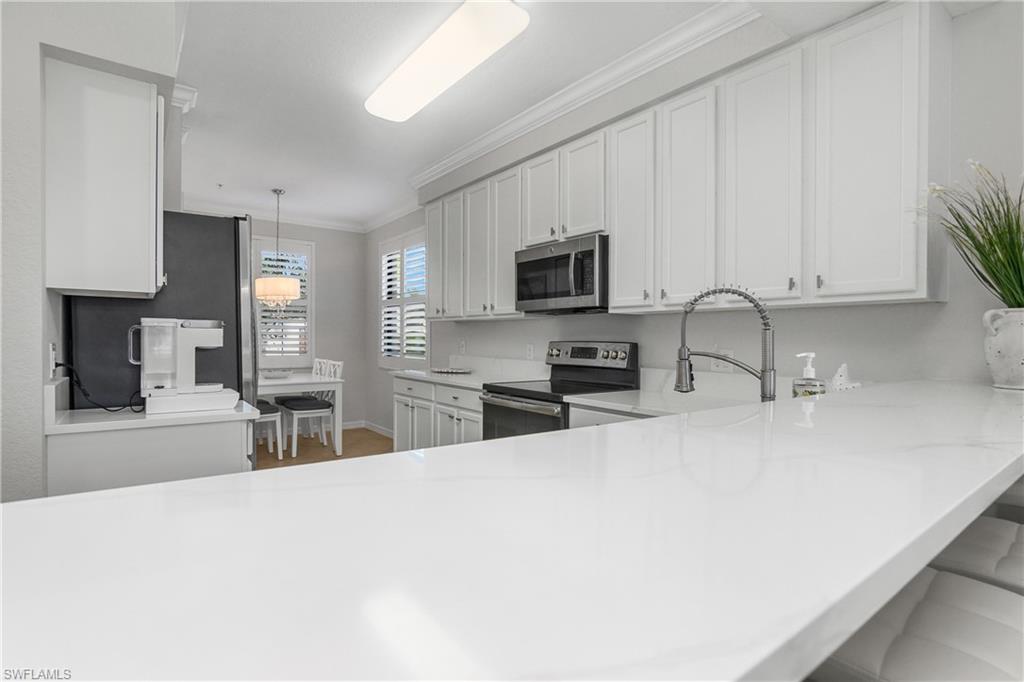 9560 Trevi Court, Unit 4811 Naples, FL 34113 - Photo 6 of 40 a kitchen with stainless steel appliances a sink a stove top oven a counter space and cabinets