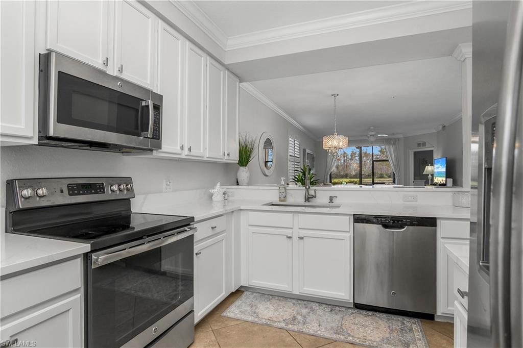 9560 Trevi Court, Unit 4811 Naples, FL 34113 - Photo 8 of 40 a kitchen with stainless steel appliances granite countertop a stove microwave and sink