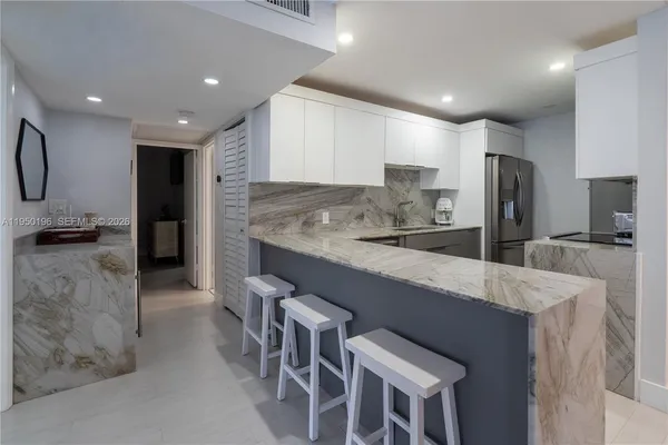 a large kitchen with granite countertop a large counter top appliances and cabinets