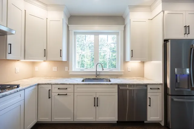 a kitchen with stainless steel appliances granite countertop a sink a refrigerator and a stove