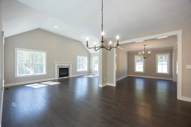 a view of an empty room with wooden floor fireplace and a window