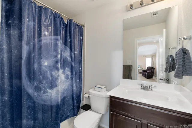 a bathroom with a sink a toilet and shower curtain