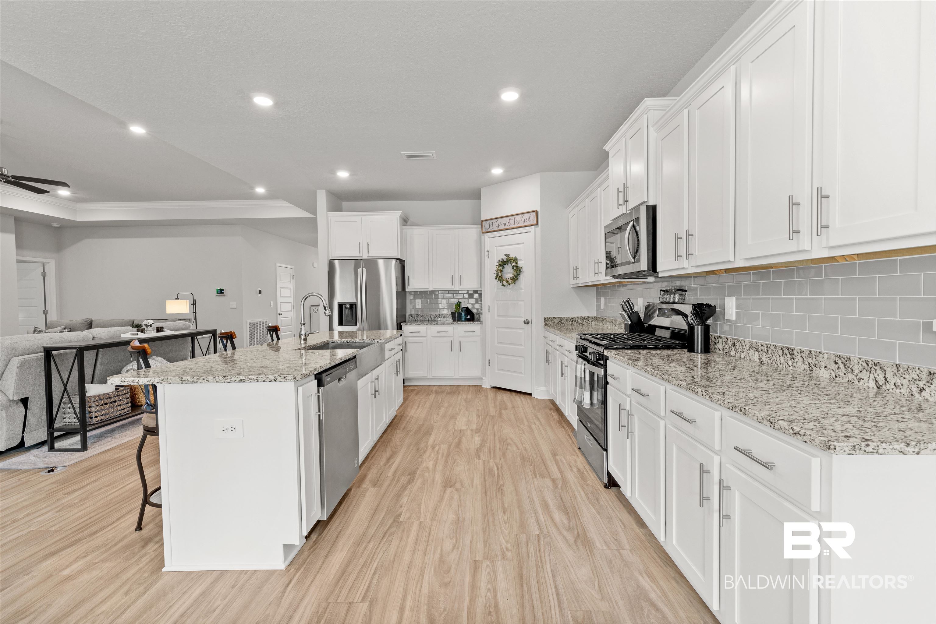 2121 Meadowview Loop Semmes, AL 36575 - Photo 21 of 46 Kitchen with appliances with stainless steel finishes, white cabinetry, a center island with sink, light stone countertops, and a kitchen bar