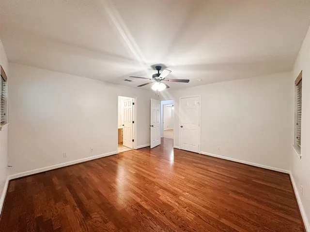 an empty room with a chandelier fan and windows