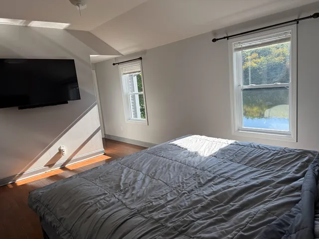 a bedroom with a bed wooden floor and window