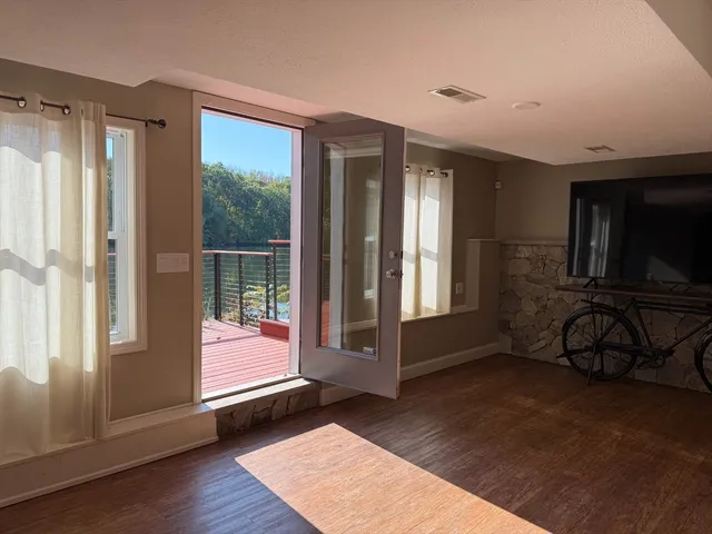 a view of an empty room with wooden floor and windows