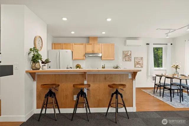 a view of dining room kitchen with stainless steel appliances kitchen island granite countertop a dining table chairs and a refrigerator