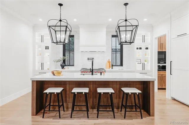 a kitchen with stainless steel appliances kitchen island granite countertop a table chairs in it and white cabinets