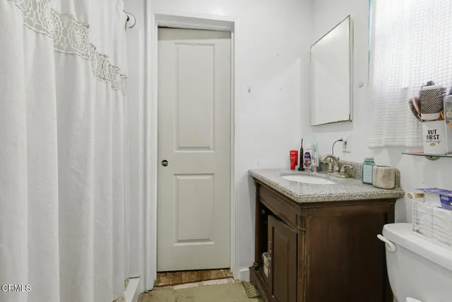 a bathroom with a granite countertop sink and a toilet