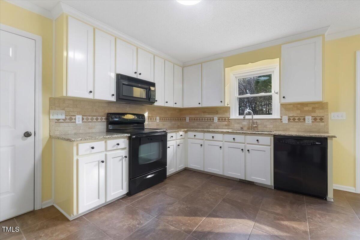 620 Trunecek Circle Raleigh, NC 27603 - Photo 6 of 53 a kitchen with granite countertop white cabinets sink and stainless steel appliances