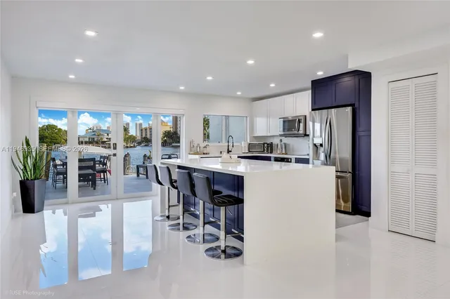 a kitchen with stainless steel appliances kitchen island granite countertop a refrigerator a stove a sink a dining table and chairs