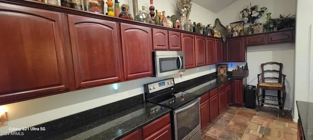 a kitchen with granite countertop wooden cabinets and a stove top oven