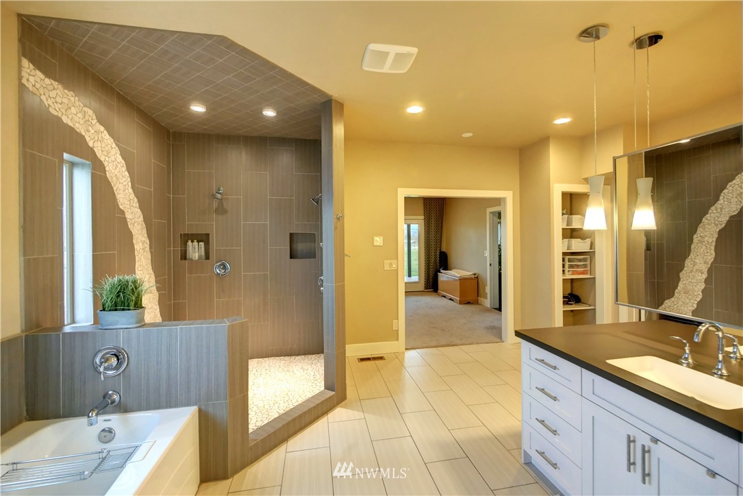 81 Jaquish Road Omak, WA 98841 - Photo 20 of 40 a spacious bathroom with a double vanity sink a large mirror and a bathtub