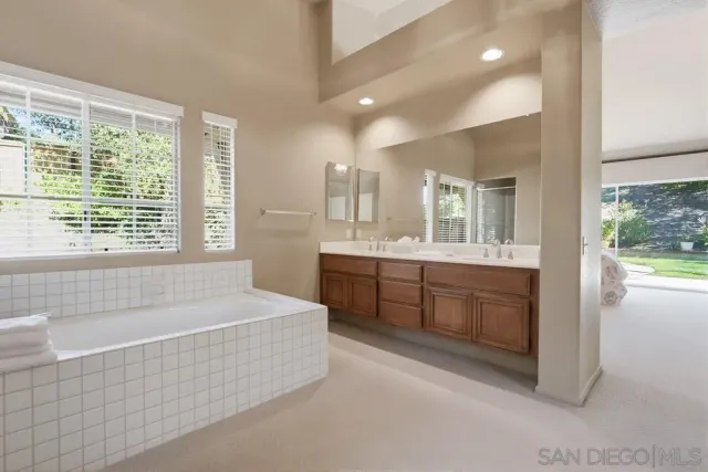 a spacious bathroom with a tub sink and mirror