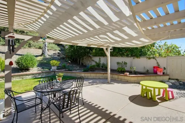 a patio with a table and chairs and potted plants