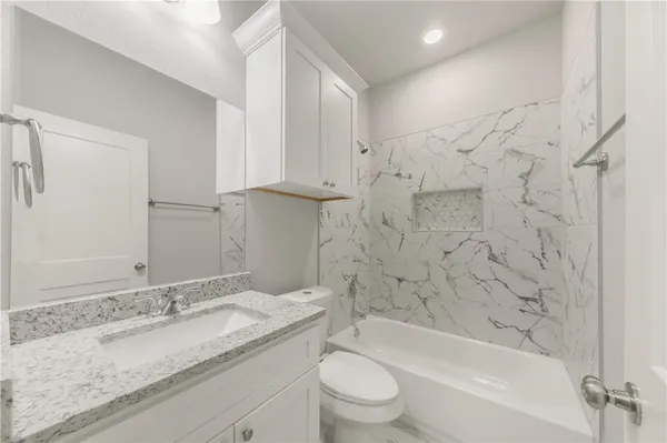 a bathroom with a granite countertop sink a toilet and bathtub