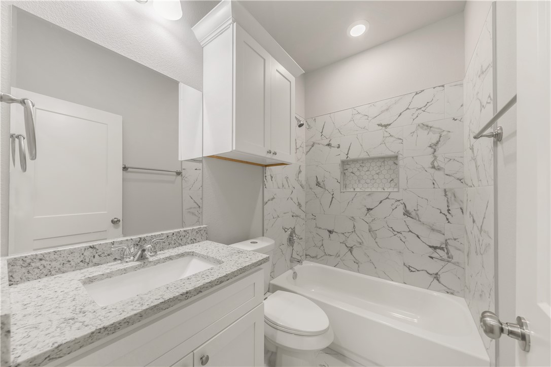 1803 Pin Oak Street Bryan, TX 77803 - Photo 12 of 17 a bathroom with a granite countertop sink a toilet and bathtub