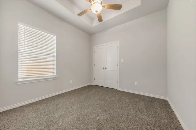 an empty room with a window and a ceiling fan