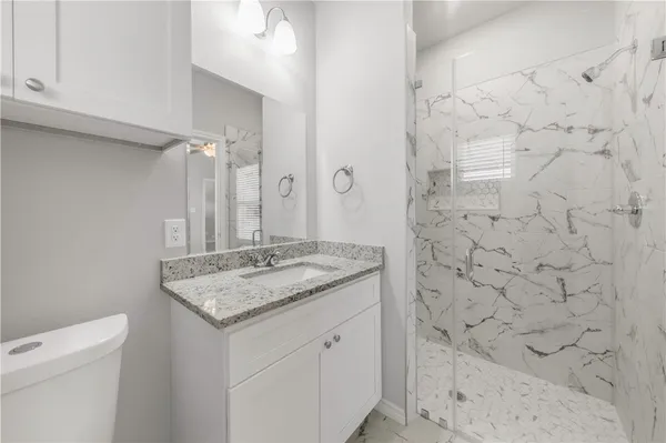 a bathroom with a granite countertop sink a toilet and shower