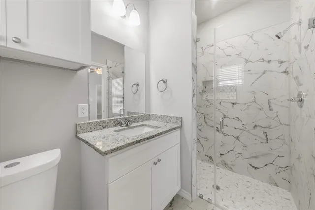 a bathroom with a granite countertop sink a toilet and shower