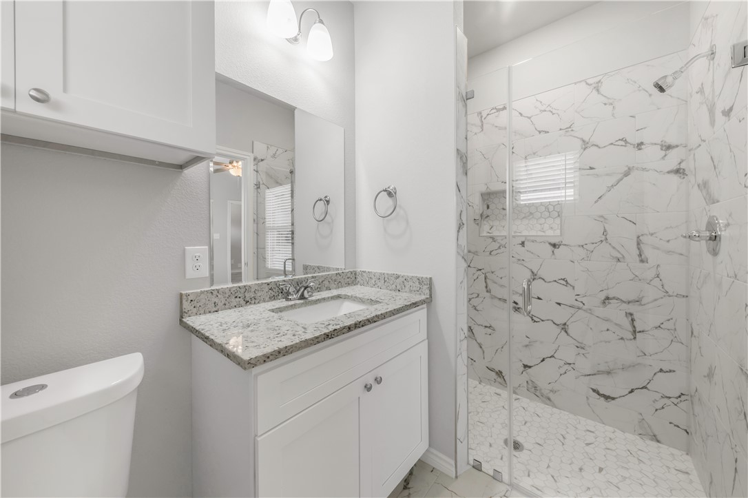 1803 Pin Oak Street Bryan, TX 77803 - Photo 16 of 17 a bathroom with a granite countertop sink a toilet and shower