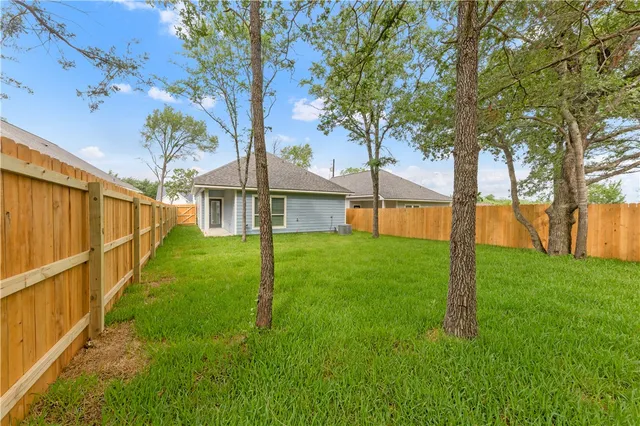 a view of a house with backyard and a tree