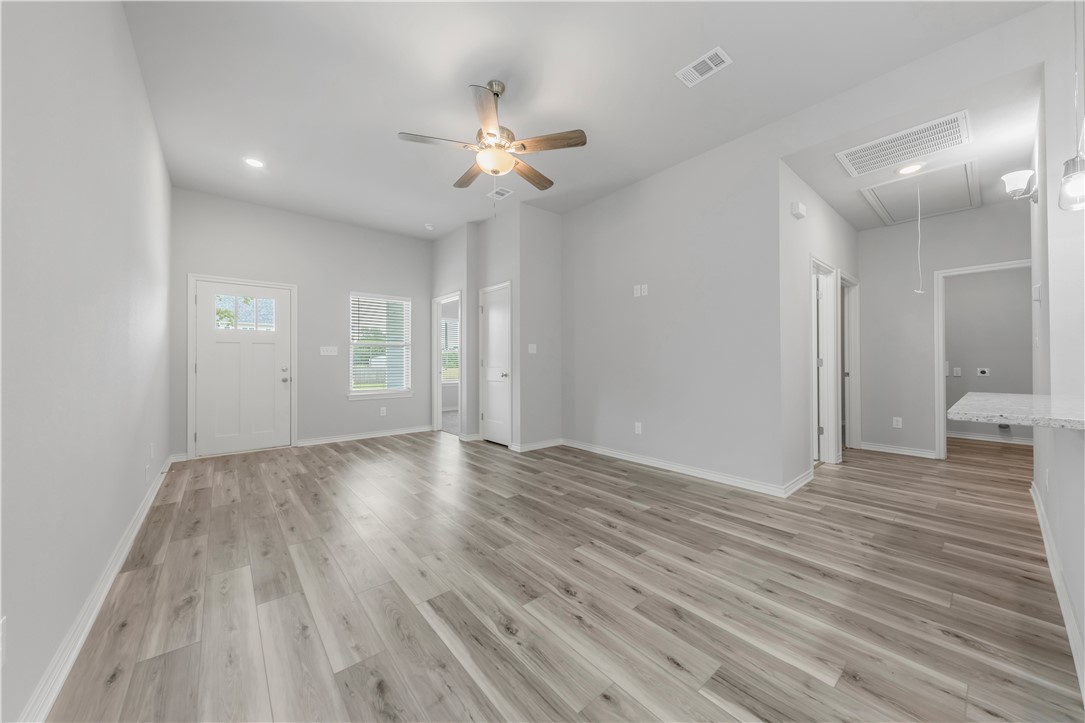1803 Pin Oak Street Bryan, TX 77803 - Photo 3 of 17 a view of an empty room with wooden floor and a ceiling fan
