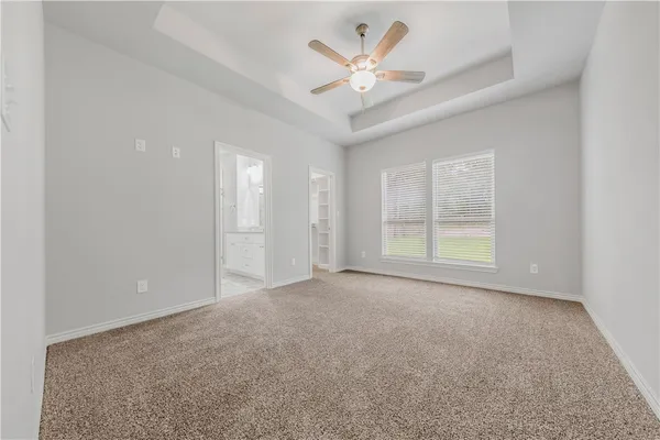 an empty room with windows and ceiling fan