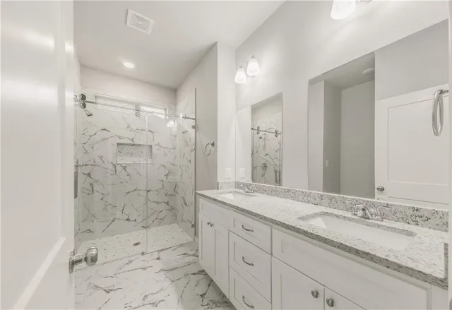 a bathroom with a granite countertop sink mirror and shower