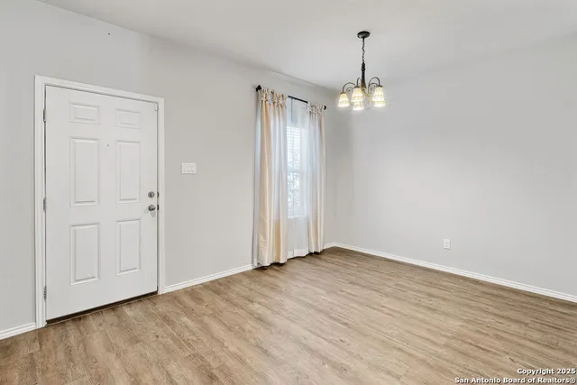 a view of an empty room with wooden floor and windows