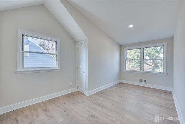 a view of an empty room with wooden floor and window