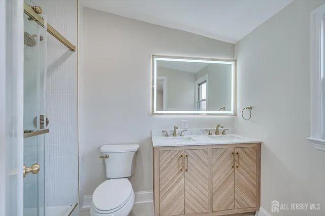 a bathroom with a granite countertop sink toilet a mirror and shower