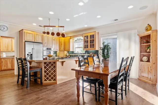 a dining room with stainless steel appliances kitchen island granite countertop a dining table chairs and granite counter tops
