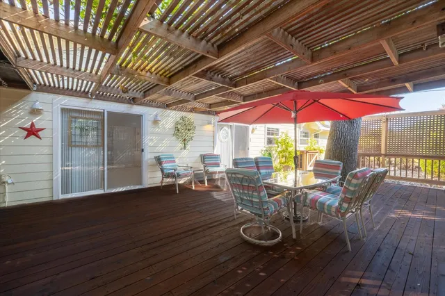 a view of a patio with table and chairs under an umbrella with wooden floor