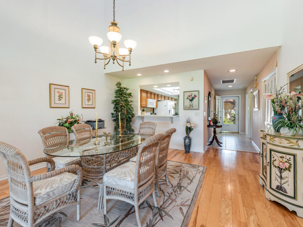 602 Augusta Boulevard, Unit 3 Naples, FL 34113 - Photo 3 of 8 a dining room with wooden floor a chandelier a glass table and chairs