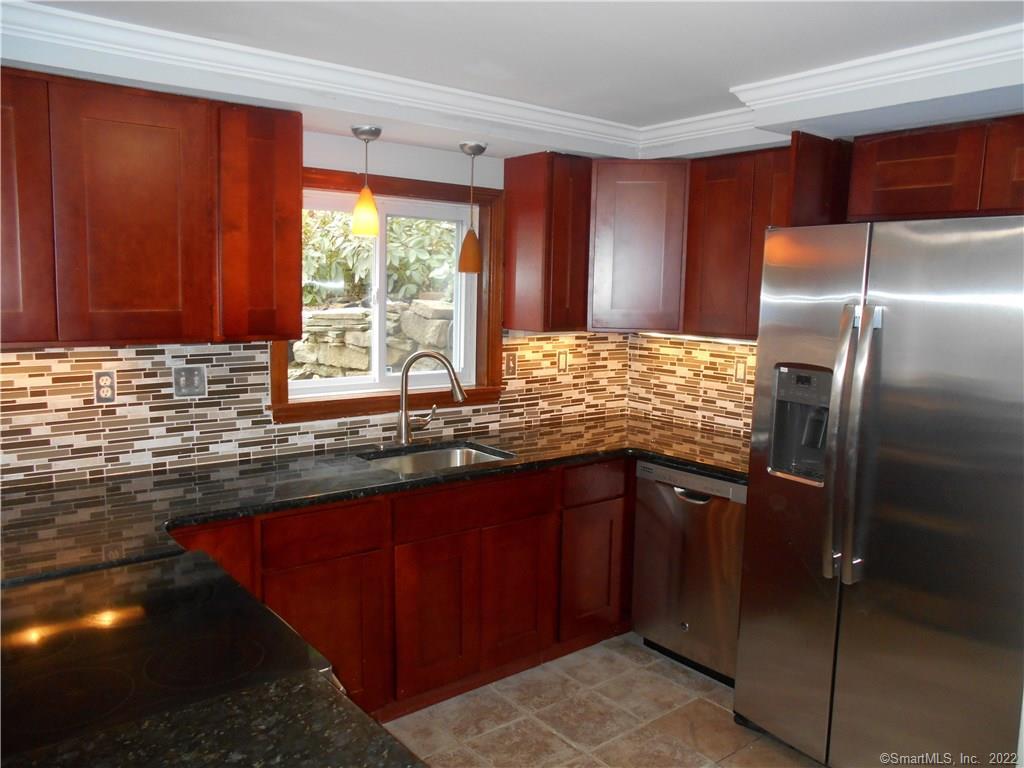 a kitchen with granite countertop a refrigerator sink and cabinets