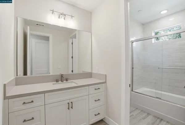 a bathroom with a shower sink vanity and mirror