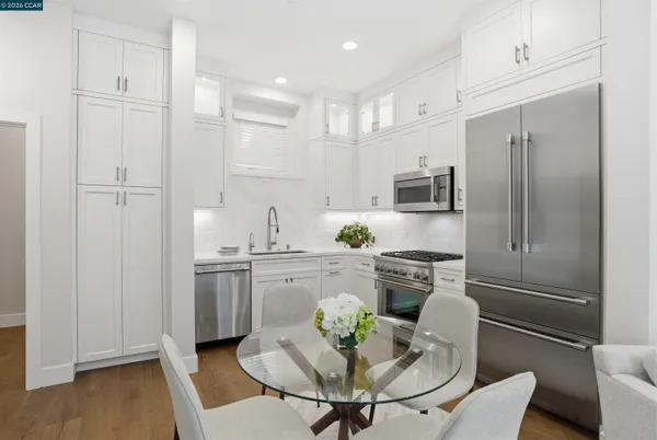 a kitchen with stainless steel appliances granite countertop a refrigerator a stove a sink a dining table and chairs