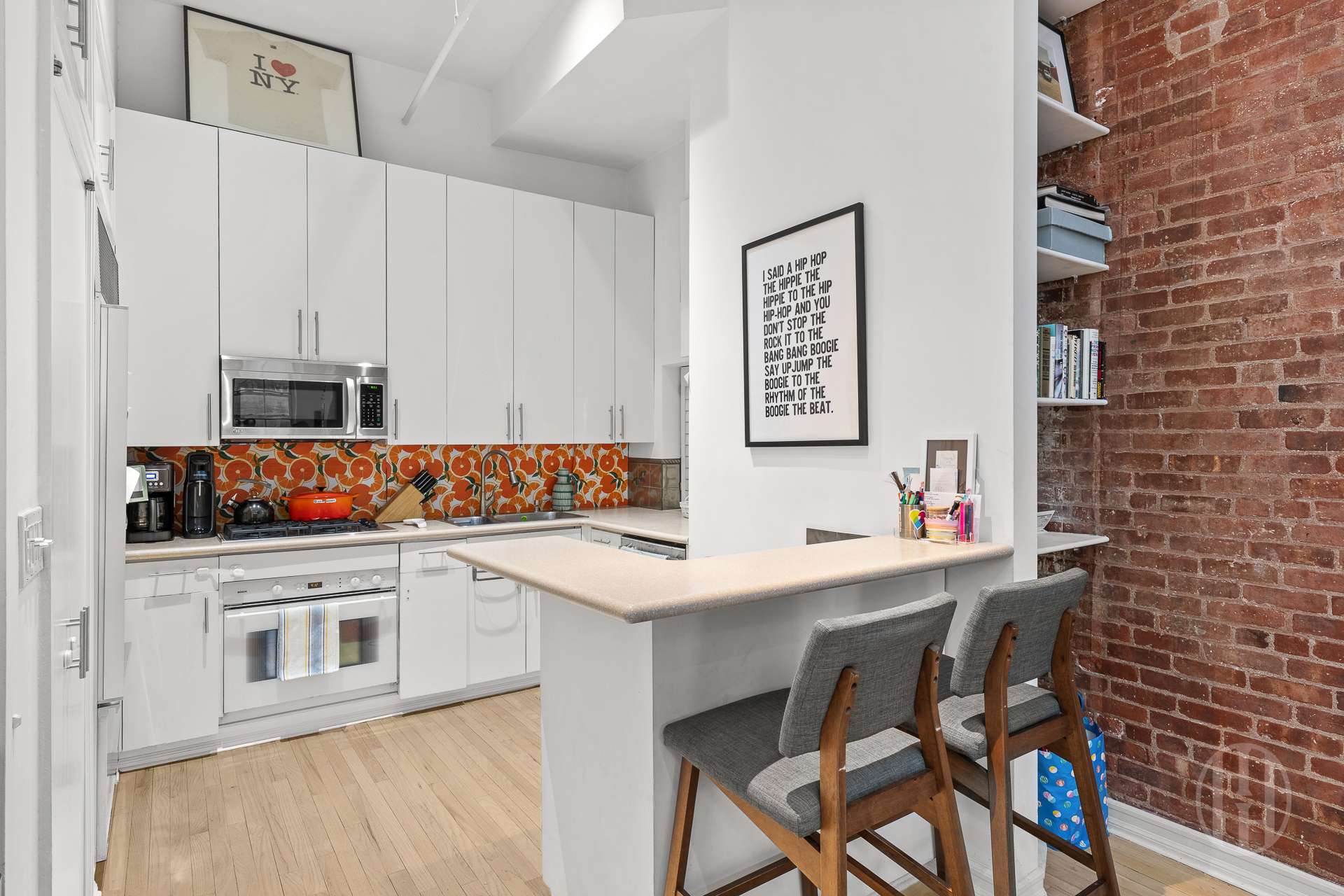 426 West Broadway, Unit 6F Manhattan, NY 10012 - Photo 8 of 13 a kitchen with stainless steel appliances a white table chairs and a refrigerator