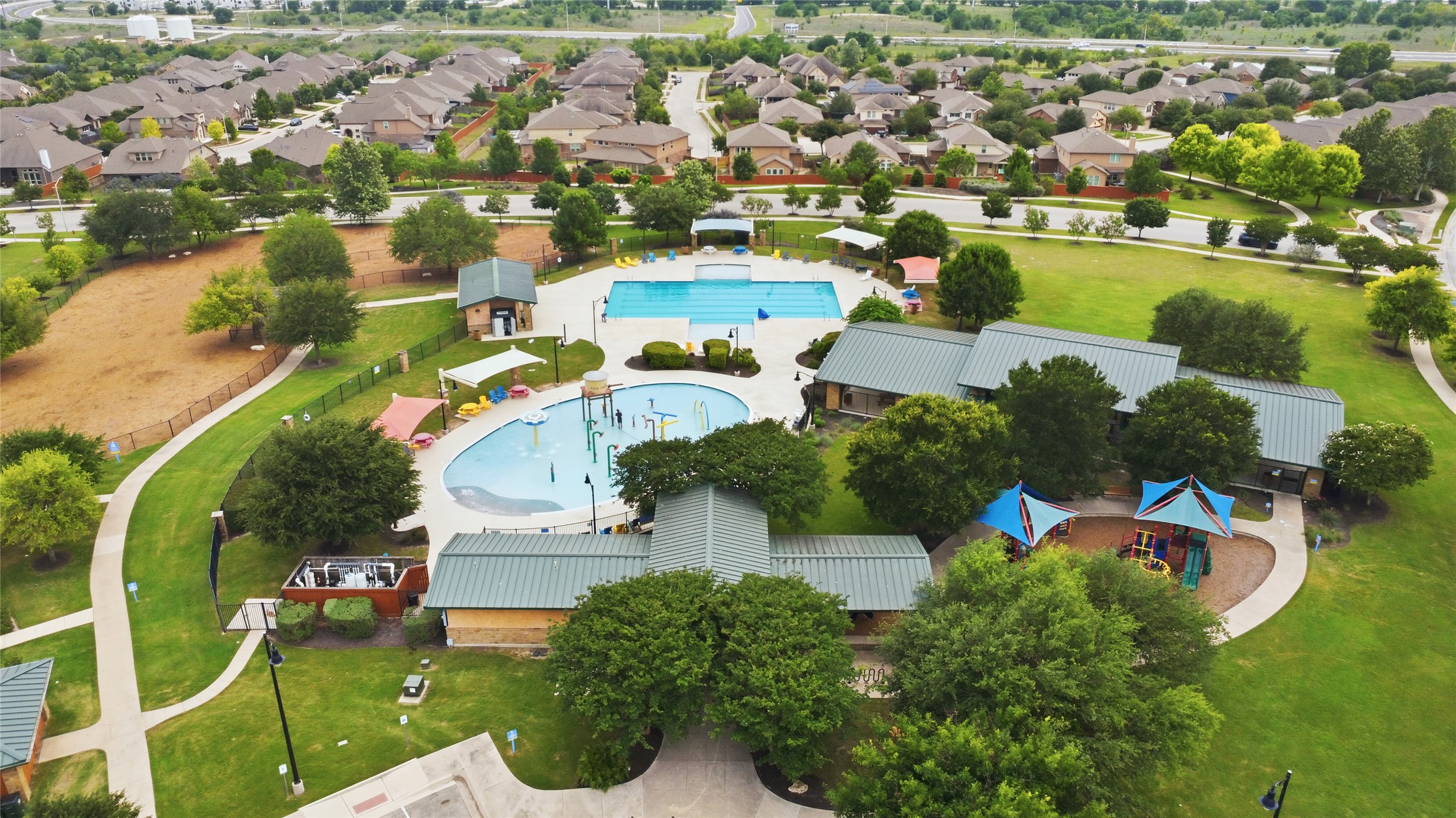 486 Pond View Pass Buda, TX 78610 - Photo 38 of 39 Community amenity center featuring multiple pools, expansive green spaces, shaded structures, and recreational equipment