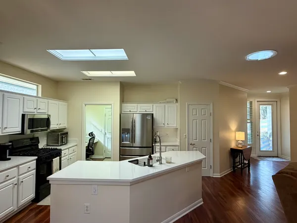 a kitchen with a sink stainless steel appliances and living room view