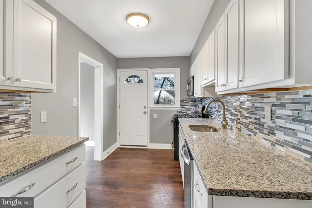 a kitchen with granite countertop a sink a stove and cabinets