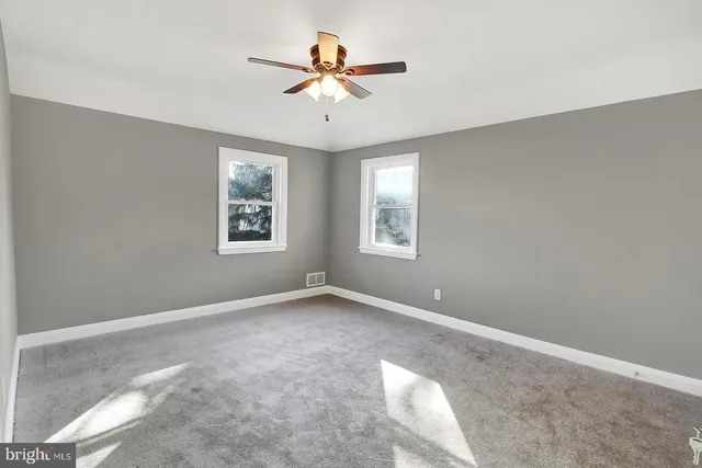 an empty room with windows and fan