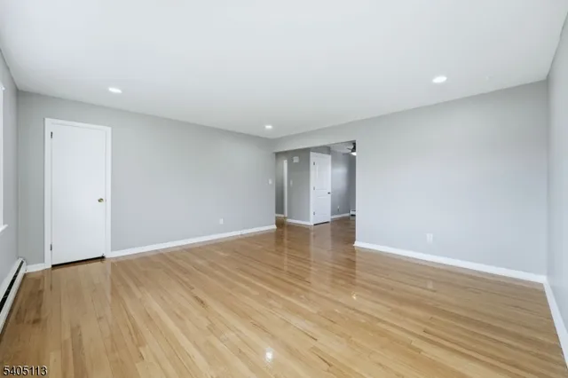 a view of an empty room with wooden floor and closet