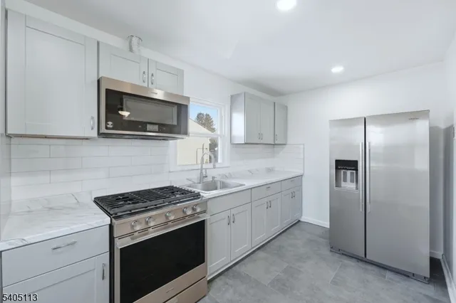 a kitchen with stainless steel appliances granite countertop a stove a microwave a refrigerator a sink and dishwasher