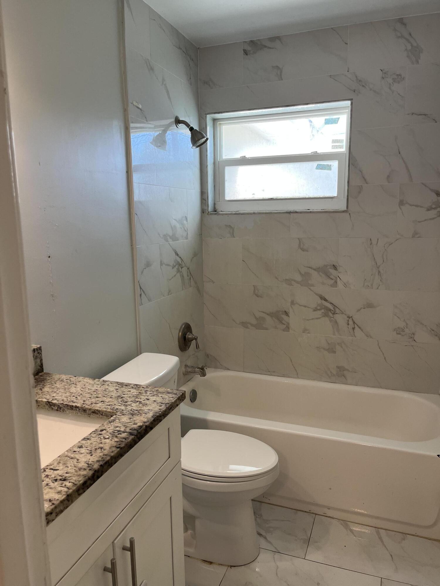 271 Southwest 4th Street Boca Raton, FL 33432 - Photo 3 of 4 a bathroom with a granite countertop toilet a sink and bathtub