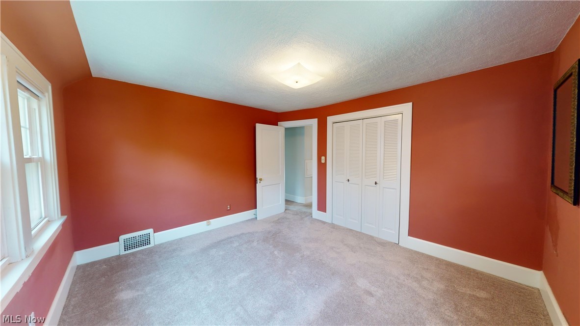 3988 Navahoe Road Cleveland Heights, OH 44121 - Photo 19 of 31 Unfurnished bedroom featuring multiple windows, a closet, carpet floors, and a textured ceiling