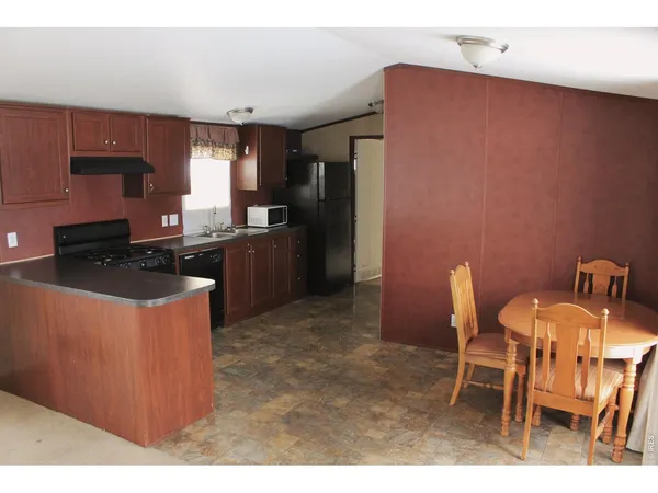a kitchen with stainless steel appliances granite countertop a stove a refrigerator a sink a dining table and chairs