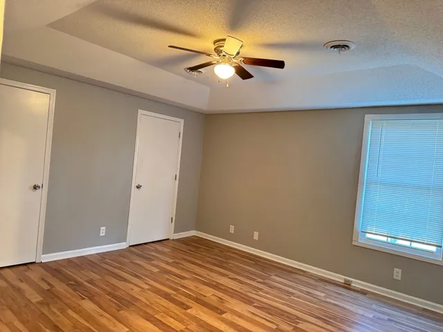 a view of a room with wooden floor and a ceiling fan
